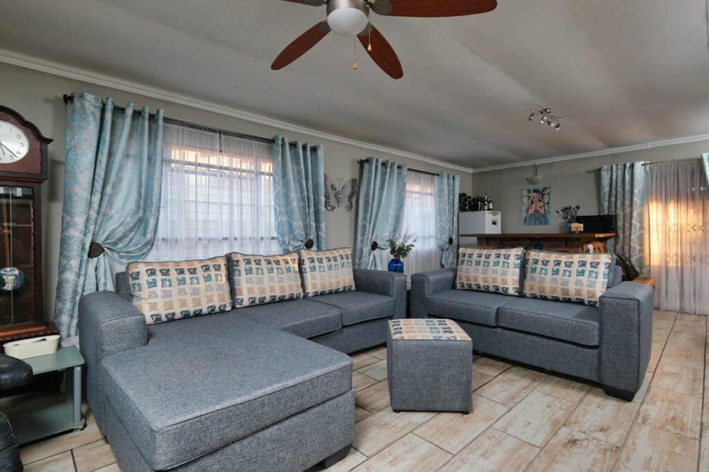 Stylish living room with blue sofas, elegant curtains, and a ceiling fan for a cozy feel.